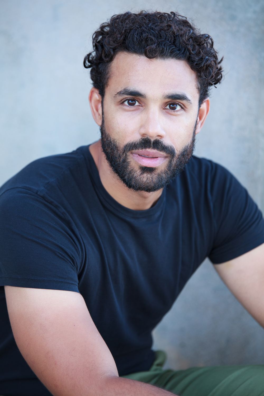 Headshot, black tee against a concrete wall