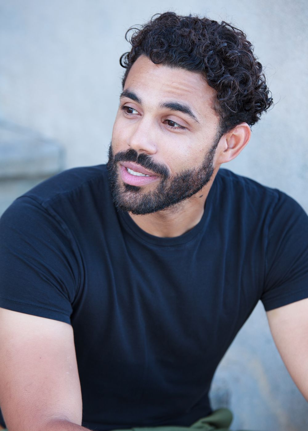 Looking off camera, black tee against a concrete wall