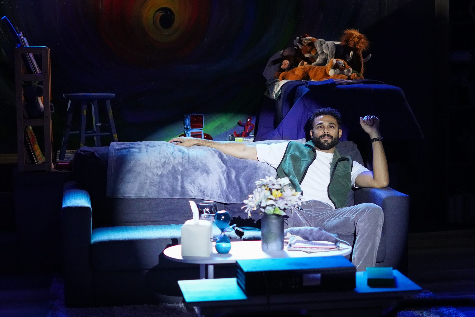 Howie sprawled on a couch under stage light in Rabbit Hole